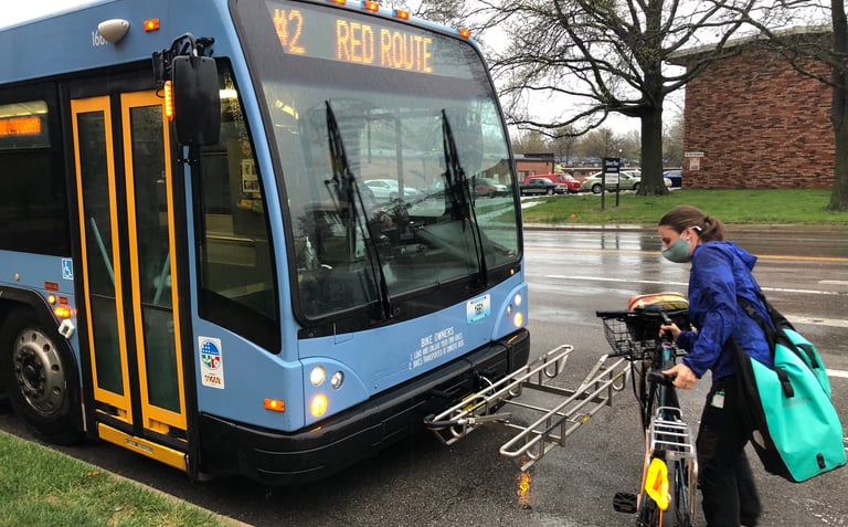 Photo of a person putting their bike on the rack installed on the front of a public bus
