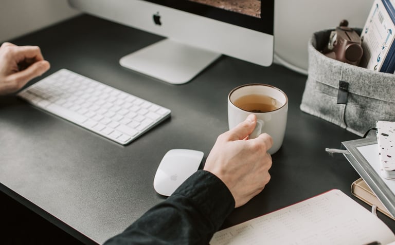 Close view of hands crossing items off a detailed checklist at a desk in Calgary, coffee cup nearby,