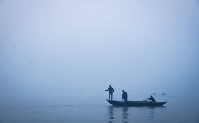 A man in a boat on a foggy day in Varanasi