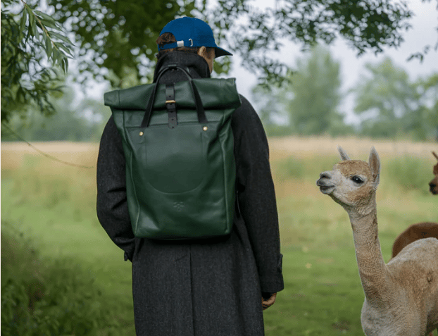 Billy Tannery Rolltop Backpack made from chestnut goat leather displayed on wooden stool