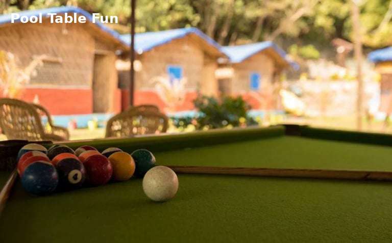 Pool table game at Jungle Lore Resort with cottages in background