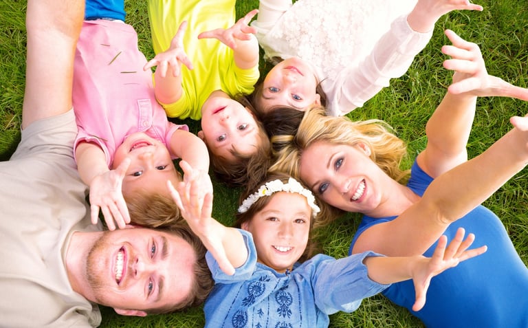 Photo d'une famille allongée dans l'herbe pour une séance de sophrologie an pleine nature