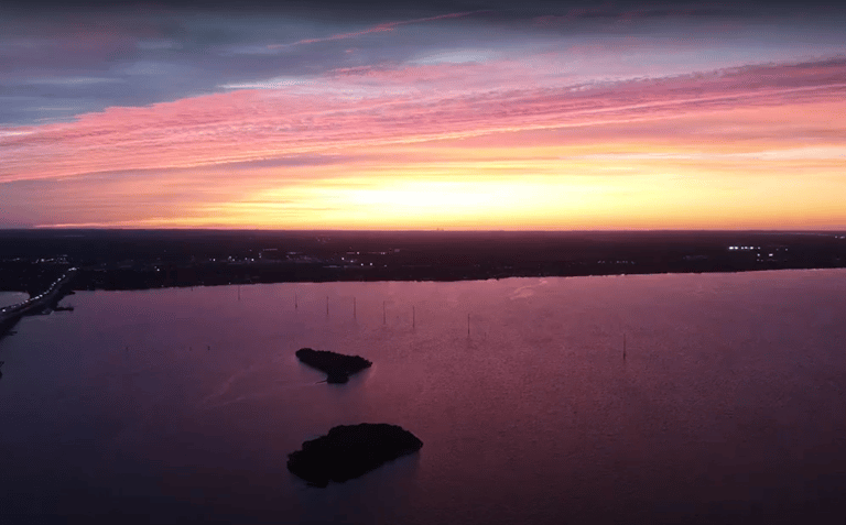 A breathtaking aerial view of a serene sunset over a large body of water.
