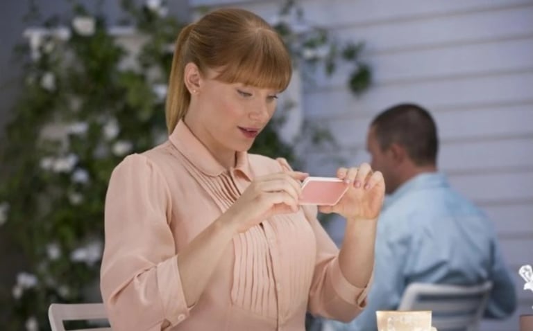 a woman in a pink shirt is holding a cell phone