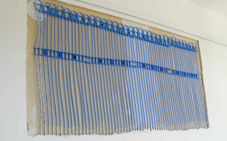 Indoor wall heating installation with blue capillary tubes integrated into the wall surface.
