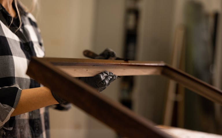 a woman in a plaid shirt and gloves holding a wood frame