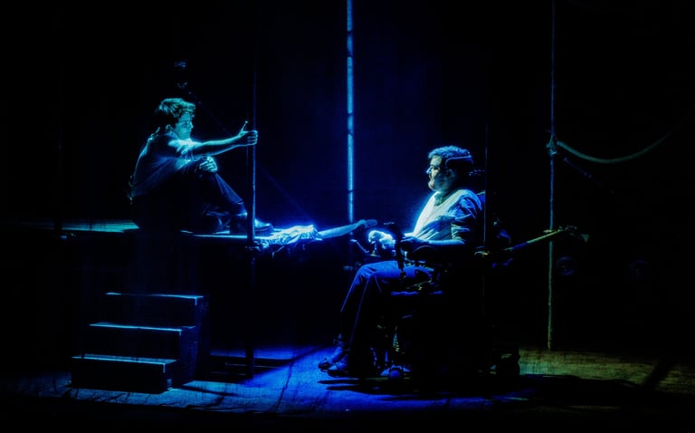 Soaked in blue light, Jamie Hale and CN Lester look at each other, surrounded by scaffolding