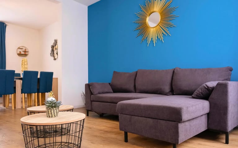 Salon lumineux avec canapé d’angle bleu, hébergement professionnel tout équipé