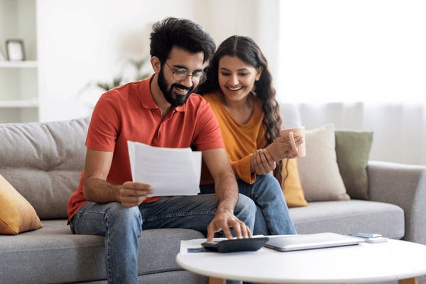 A couple reviewing their budget on a laptop or writing in a budget planner for wedding