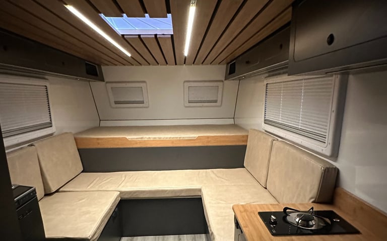 salón interior de una célula camper con luces led, cama y sofas