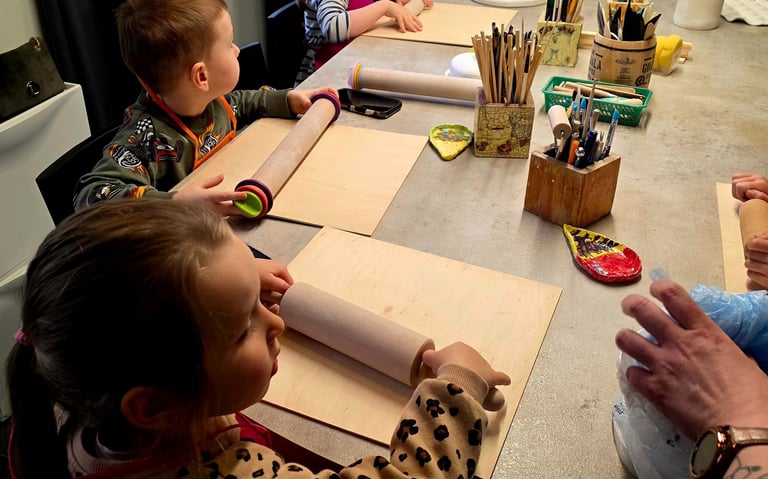Young children using rolling pins during a creative pottery workshop and ceramics class for kids.