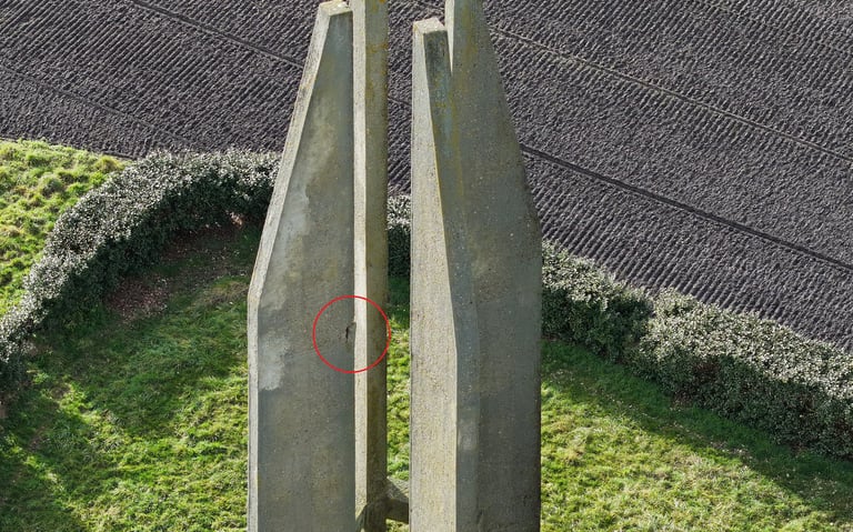 Gros plan d'un pilier de monument en béton avec un petit trou encerclé en rouge pour inspection.