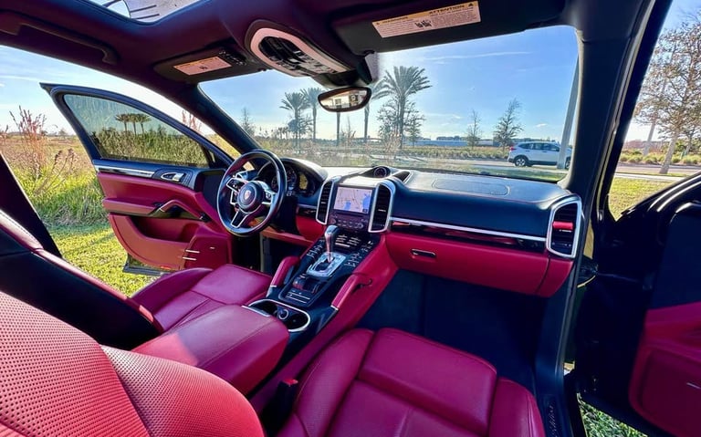 Interior of a luxury SUV with red leather seats and black trim, freshly detailed and parked under clear Florida skies