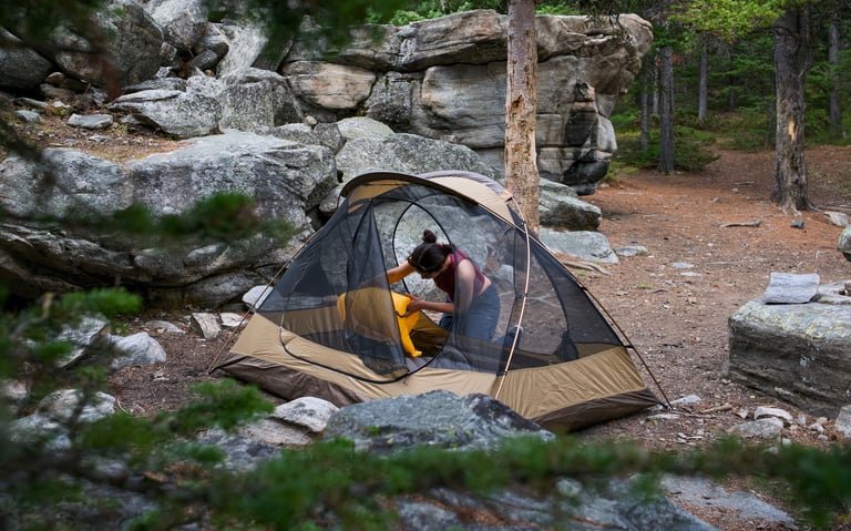 Woman getting a campsite ready by inflating sleeping pads