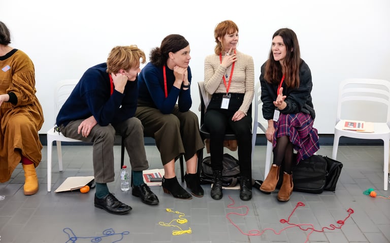 Four adults listening and thinking with smiles on their faces.