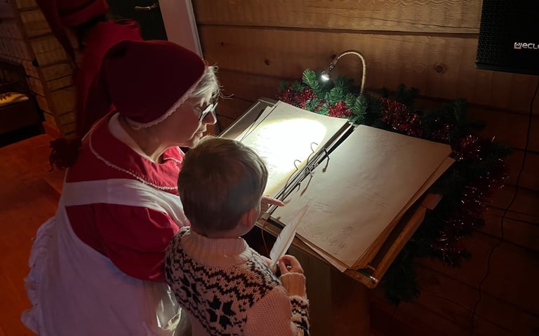 Mrs Claus helping a boy to write a message