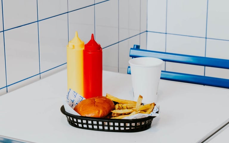 Burger amb patates i salses servides en una taula de Flipa amb estètica minimalista blava i blanca
