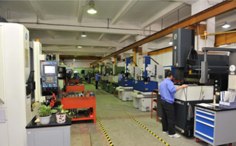Industrial mould precision machining workshop with workers operating CNC milling or lathe equipment.