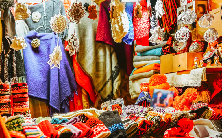 Handmade wool mittens, hats, and scarves displayed at a festive Christmas market stall.