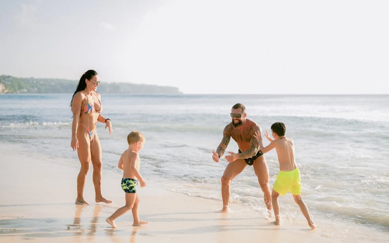 Children playing in the shoreline waves during a fun family beach photography session at Dreamland Beach Bali.