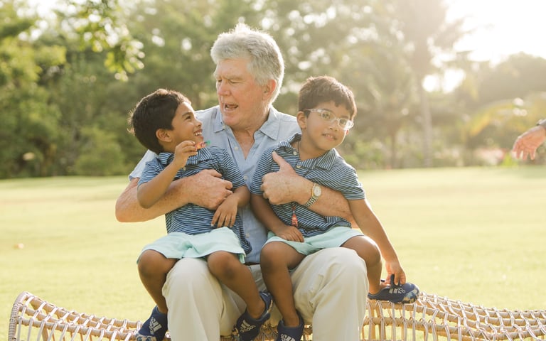 grandfather sitting and hugging his grandchildren on a woven chair at rimba by ayana bali during relaxed family photography