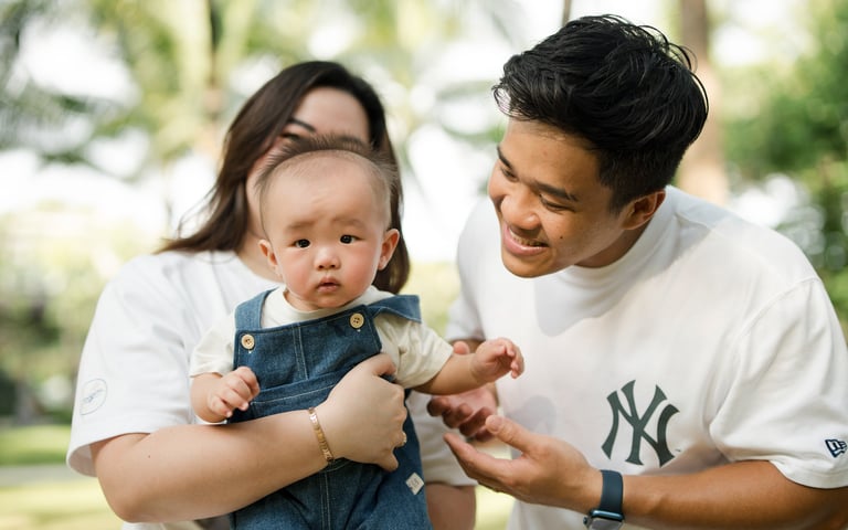Parents holding their baby during a relaxed family photography session at The Apurva Kempinski Nusa Dua Bali