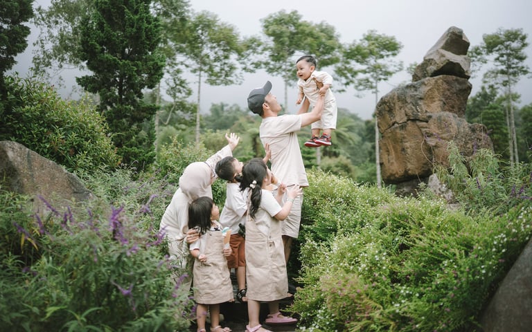 Father lifting child in flower garden during a family photography session at Bali Farm House Bedugul Bali.