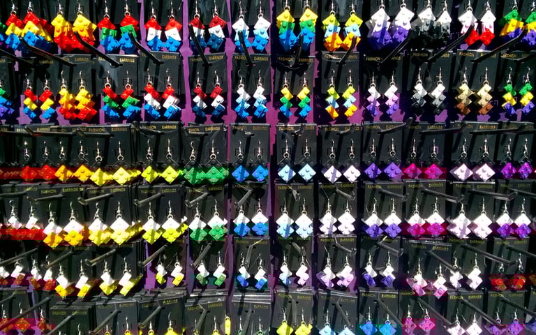 A vibrant display of handmade colorful LEGO earrings hanging on black retail display cards.