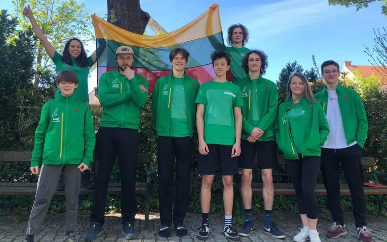 a group of people standing in front of a bench holding Lithuanian flag
