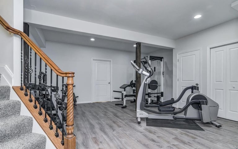 Exercise room with grey wood pattern LVT, several closets, and gym equipment
