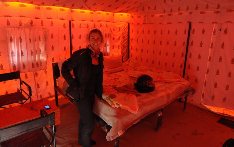 a man standing in a tented room with a bed and chairsTracey Billington riding the Leh to Manali high