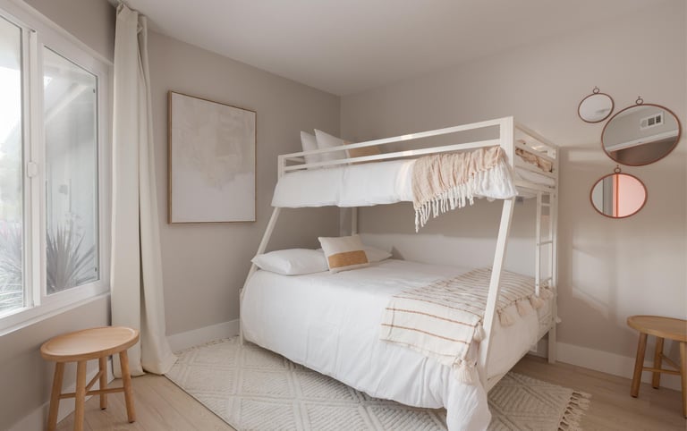 a white bunk bed in a beige room with a window
