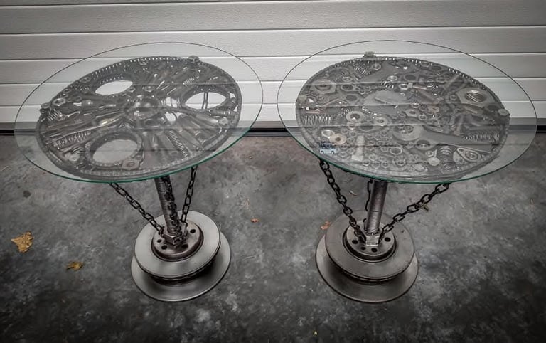 Two steampunk tables crafted from recycled metal tools with round glass tops