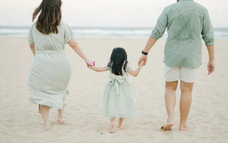 Parents and daughter walking hand in hand along the shoreline during a family photography session in Bali.