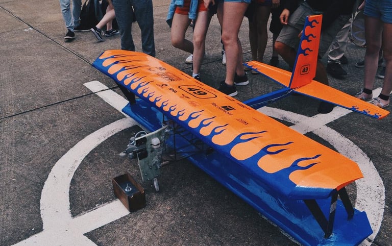 Biplano azul e laranja pousado na pista, na frente de pessoas
