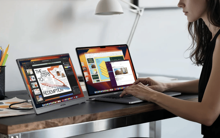 a female student sitting at a desk with a laptop and a portable monitor