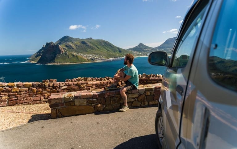 a man sitting on a ledge overlooking a body of water