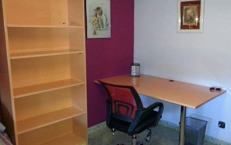 Habitación con estantería y amplio escritorio