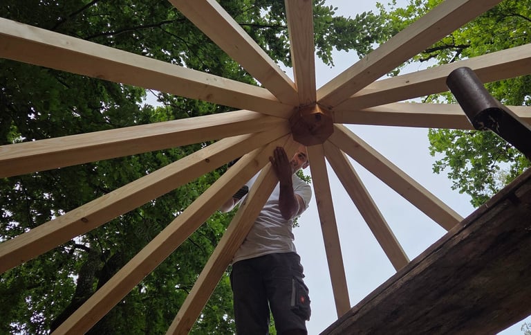Handwerker bei der Montage der sternförmigen Dachkonstruktion eines Holzpavillons von Holztechnik Volk am Ammersee