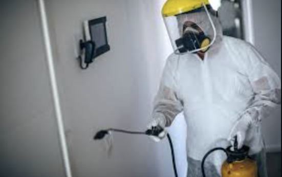 Man in hazmat suit disinfecting room