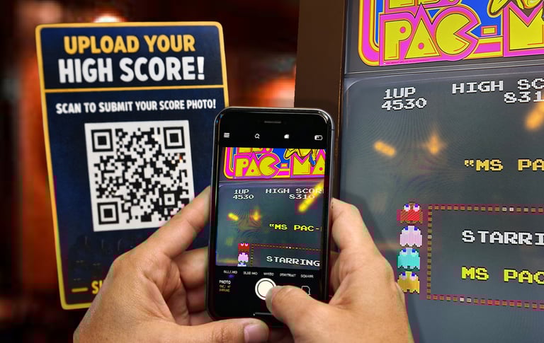a person using using a QR code to snap and send their high score on pacman