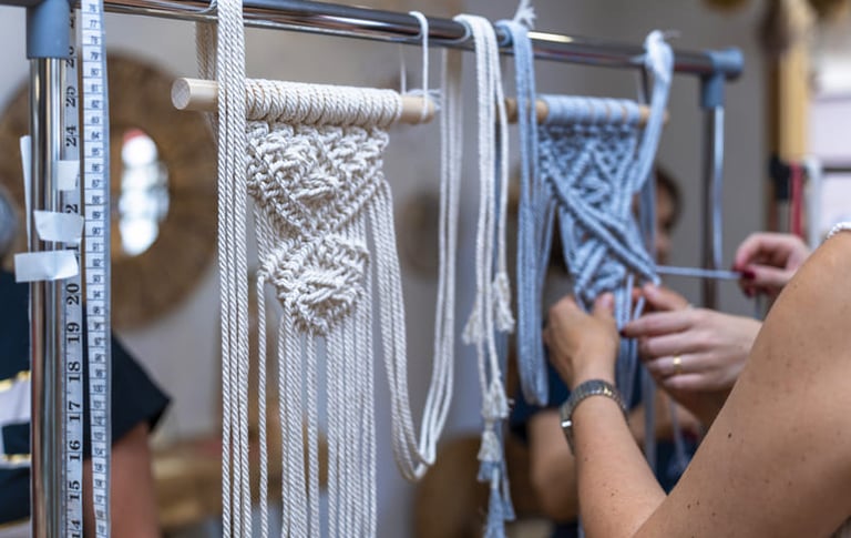 Proyecto de arte de macramé hecho a mano en progreso, colgado en un perchero metálico.