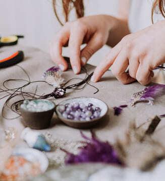 Artesana creando un collar artesanal de cuentas moradas con plumas