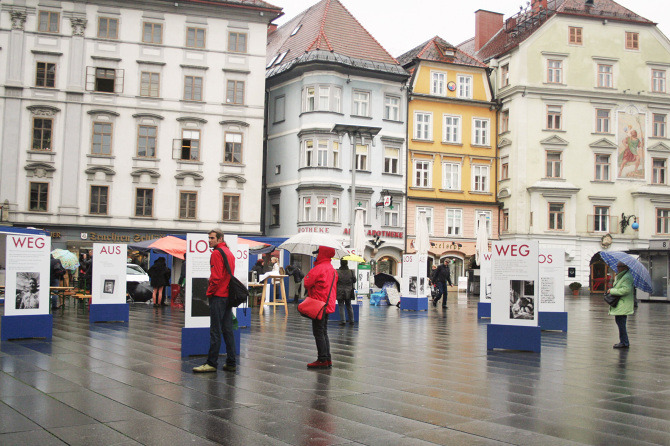 Menschen gehen durch die Ausstellung "Aus weg los!" auf der Grazer Hauptplatz.