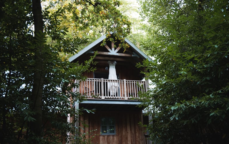 a wedding dress hanging from a lodge treehouse