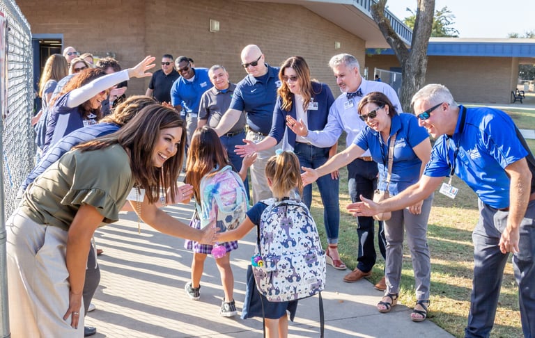 Teachers giving students high-fives as they walk into class
