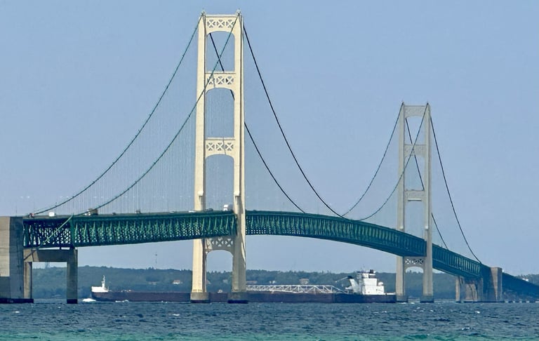 Large black and white freighter H. Lee White passing under the Mackinaw Bridge.