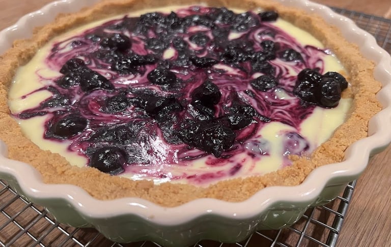 Freshly baked blueberry swirl tart with a buttery short crust in a fluted ceramic dish.