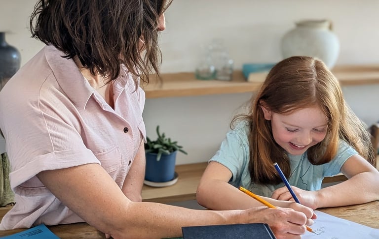 A Kent tutor helping a year 4 key stage 2 child with English and Maths at a wooden table.
