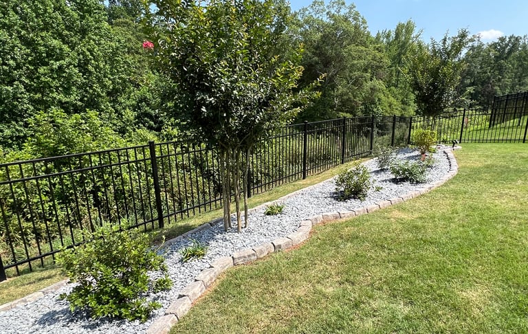 Created backyard flowerbed along the black fence with azaleas, butterfly bushes, roses, slate mulch and stone border.